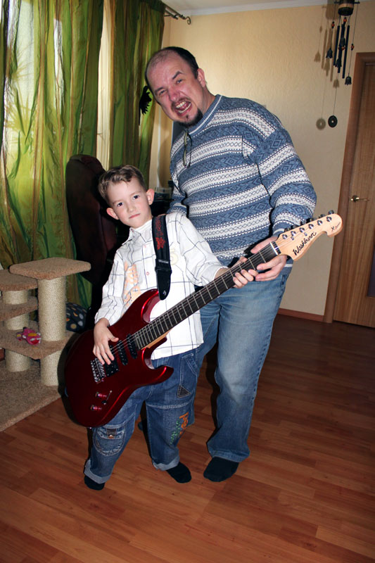 Anatoly Balyaev playing guitar with his son