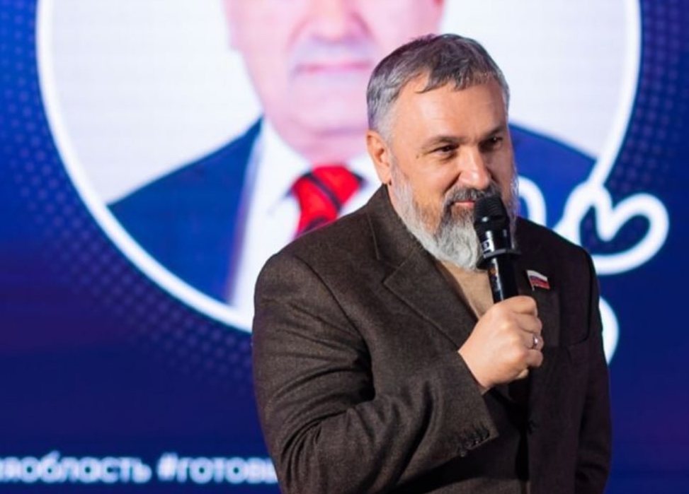 Василий Суханов с бородой, которую не бреет с конца февраля 2022 года; на экране за спиной — его прежний портрет
