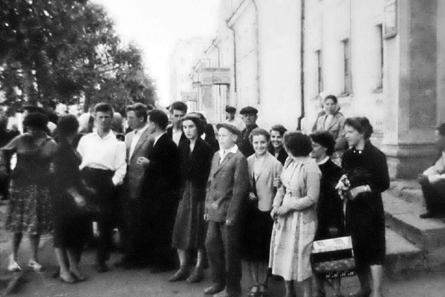 A group of people on the street by a house, a suitcase in hand, summer clothing, 1965